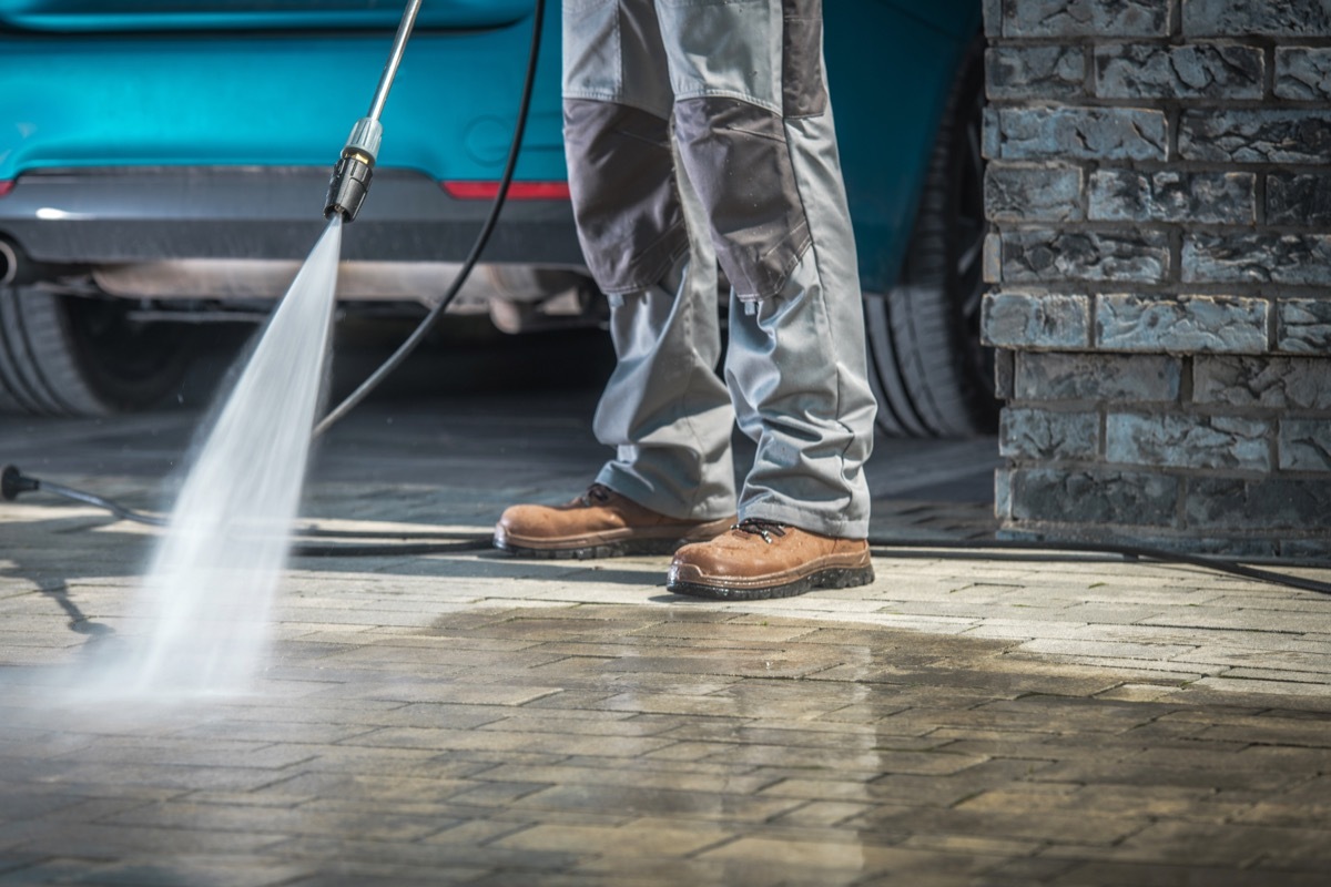 man pressure washing his driveway