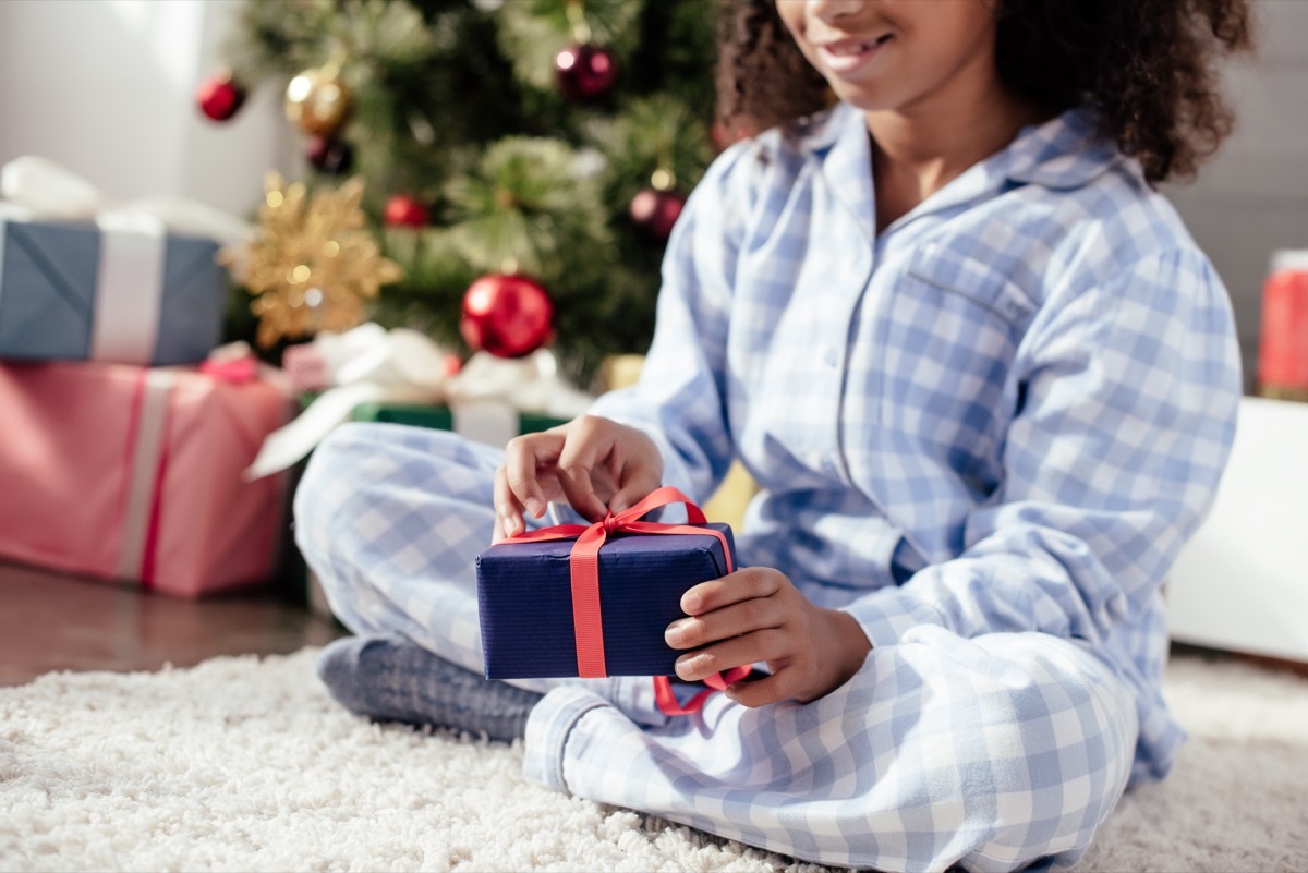 Little girl opening Christmas presents in pajamas