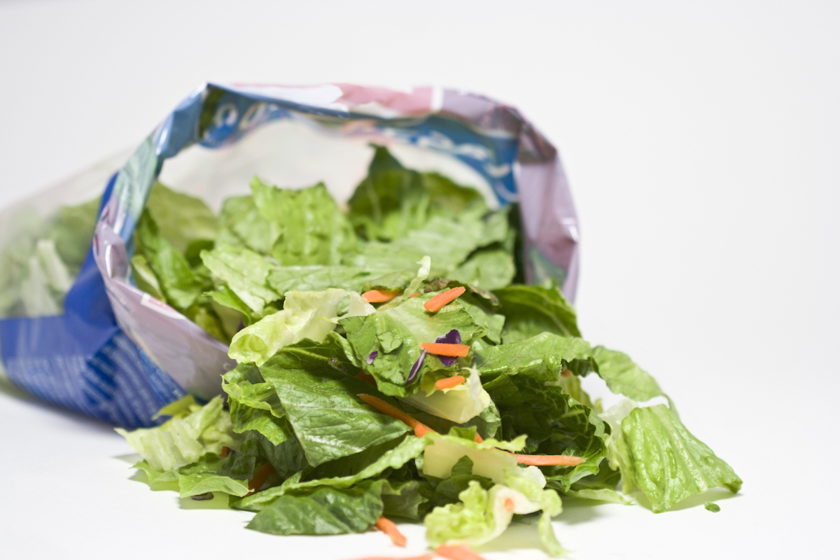 Open bag of salad on white background